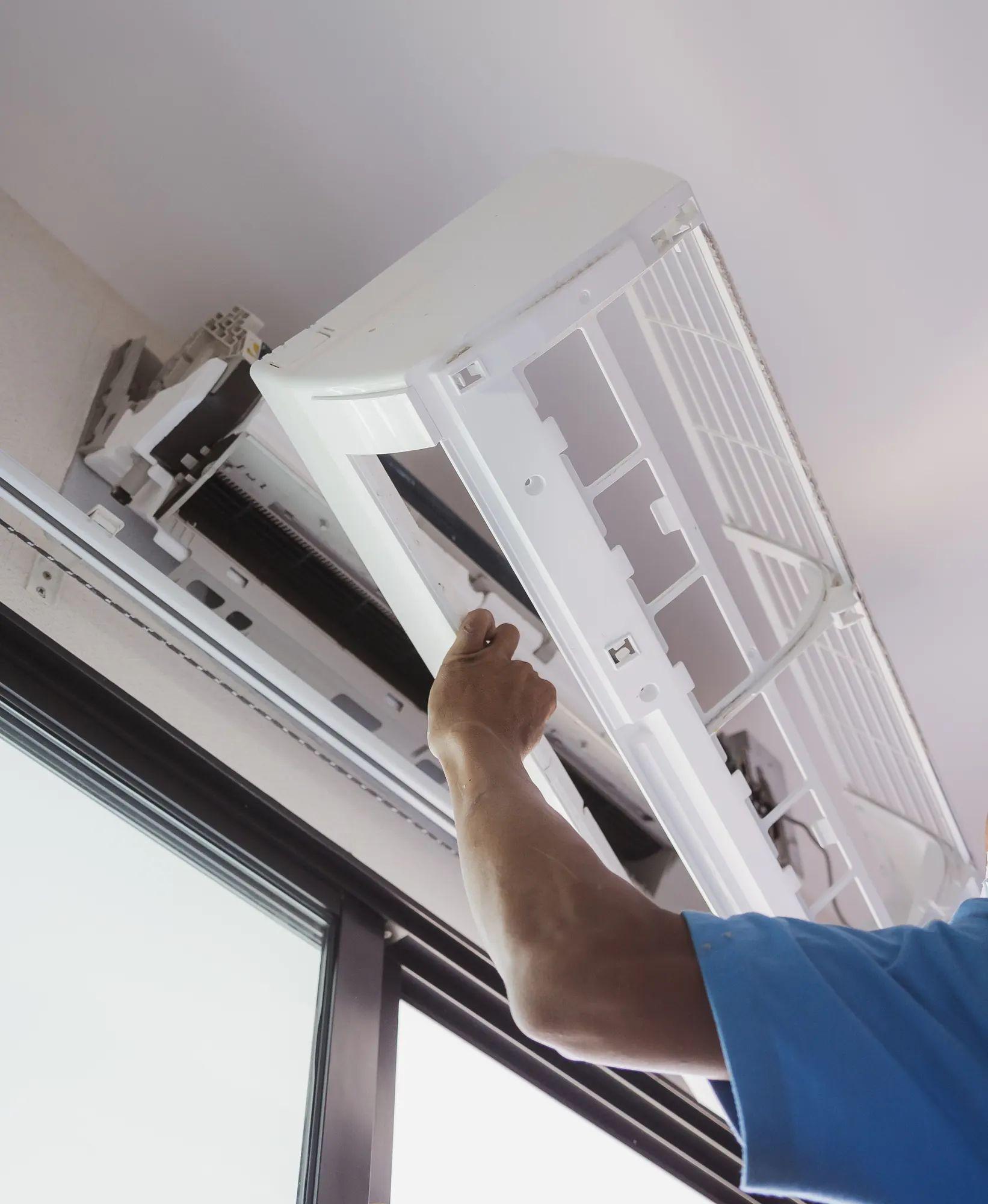 Técnico abriendo la carcasa de un aire acondicionado para limpiar los filtros durante el mantenimiento