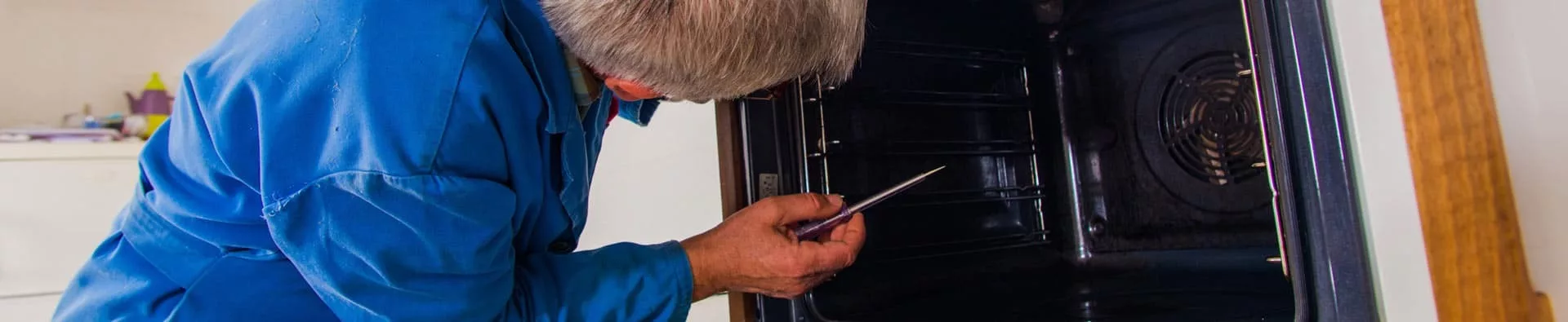 Técnico con un destornillador revisando el interior de un horno abierto